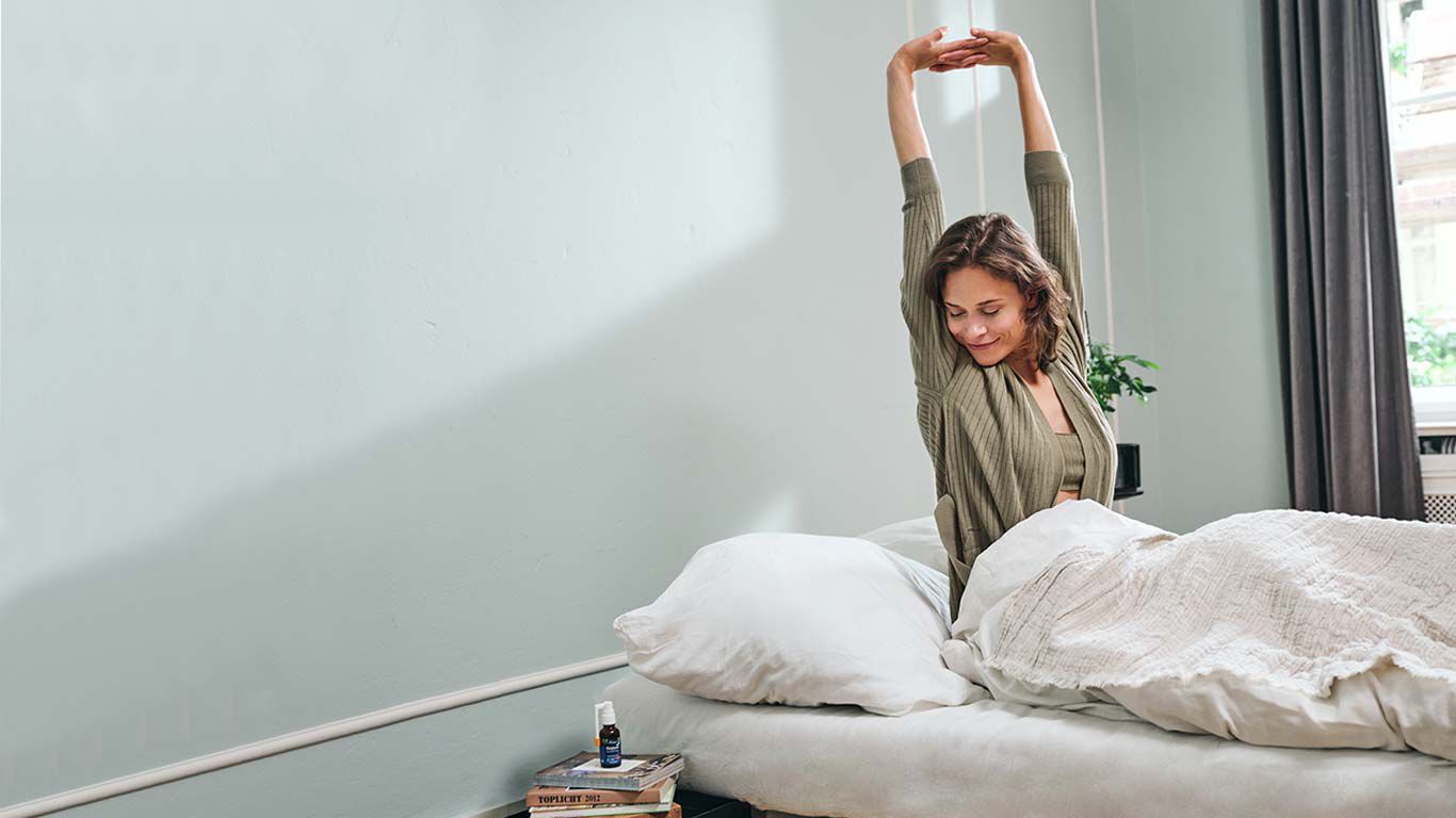Een vrouw met bruin haar strekt zich uit in haar bed.